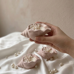 Hand holding a small aesthetic shell candle with shimmering wax pearls, luxury coastal home decor.