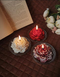 Three hand-poured peony flower shaped candles in red, ivory, and multi-colour.